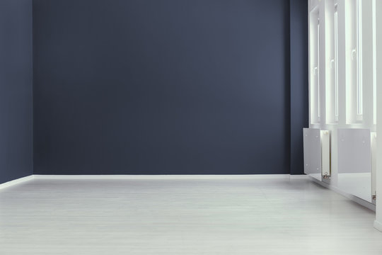 Empty minimal navy blue living room interior with copy space and grey floor. Real photo. Place for your sofa