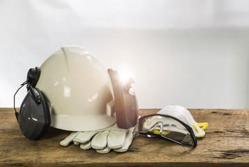 PPE onsist with White safety helmet (hard hat) with ear muff attached,Respiratory protection, Pair of leather gloves and transparent plastic glasses, Engineering and construction concept.