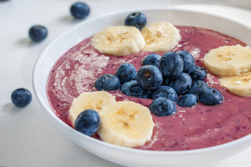Vegan fruit smoothie with blueberries and banana on white background, close-up, day