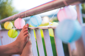 Bunte Papierlaternen an einem lauen Sommerabend, Frauenfüße an Veranda