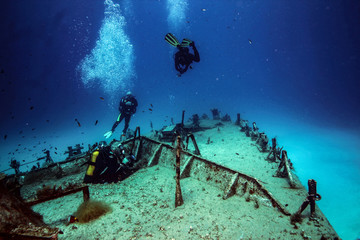 Scuba divers exit the wreck of a patrol boat.
