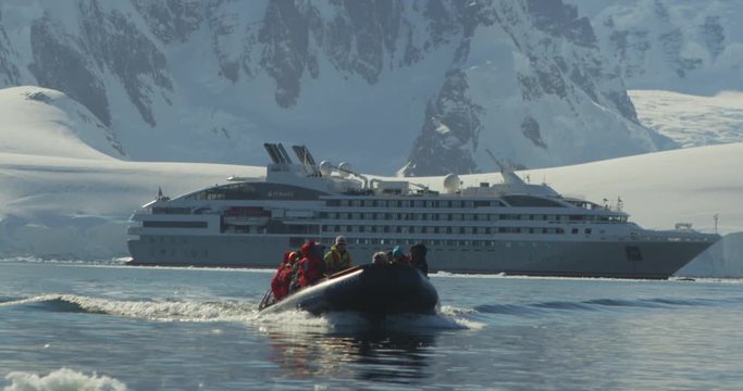 A zodiac with passengers leaves the ship to explore icebergs in Antarctica.
