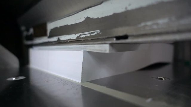 Paper cutting process, close-up, big industrial cutter for cutting paper shears - guillotine machine. Slow motion 250FPS