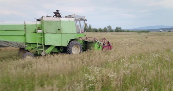 Aerial shot: An old chap combine harvester collecting ripe wheat