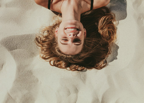 Close Up Of Woman Relaxing On Beach Sand