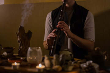 Man playing japanese bamboo flute - shakuhachi. Warm romantic illumination, low key. Relaxation, meditative and traditional music concept. Close up shot