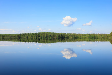 Sky reflects from still lake at summer day - 218355672