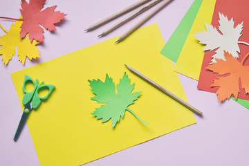 Making maple leaf from colored paper with your own hands for decoration of greeting card. Handmade crafts. Hello Autumn concept. Children's DIY. Copy space. Step 1. Circle the stencil.
