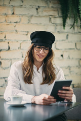 Young modern woman sitting in cafe and using tablet.