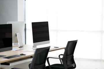 Modern office with documents and computers on the table.