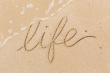 Fototapeta na wymiar Word Life written in sand beach, wave.