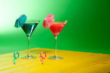 Exotic cocktail drinks. Summer vacation beach party alcohol. Fun blue and pink cocktails with paper umbrellas and curly straws.