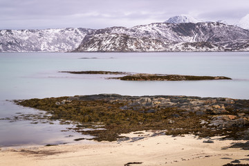 View of beach in Arctic Norway during Polar night with snowcovered mountains in background, Somoya, Norway.