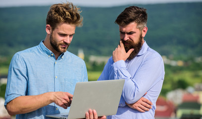 Business partners in formal wear with laptop or notebook taking advantages of mobile internet...