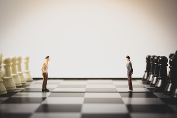 Closeup side view miniature businessman on chess board.