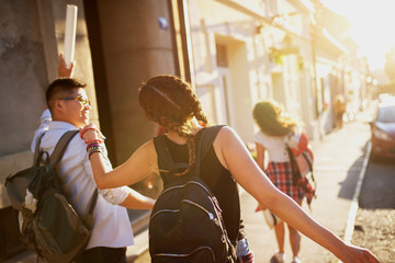 Young excited student tourists walking in a city streets and having fun on a hot summer day.