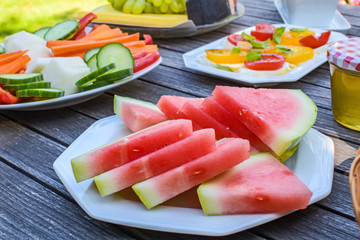 Wooden breakfast table in the garden with various vegetarian and vegan snacks
