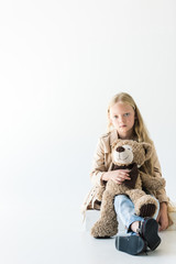 full length view of beautiful stylish kid holding teddy bear and looking at camera isolated on white