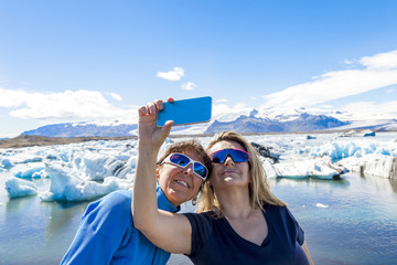 two female tourists taking a selfie with a smart phone