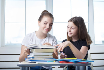 Obraz premium Teenagers teens students are sitting at the table with books studying