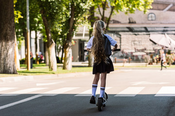 rear view of cute little kid with backpack riding scooter on street © LIGHTFIELD STUDIOS