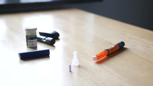 A circulating shot of various diabetic equipment like a glucose meter and a short-acting insulin pen.
