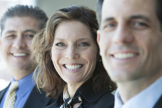 A closeup portrait of a row of multi ethnic business people, with focus on the Caucasian businesswoman.