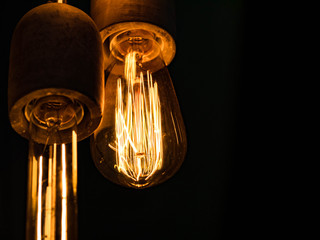Different types of vintage glowing light bulbs on black. Edison lamps