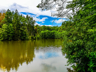 Beautiful trees and sky reflecting on a calm lake surface. Taken in Bavaria, Germany on a sunny fall day.