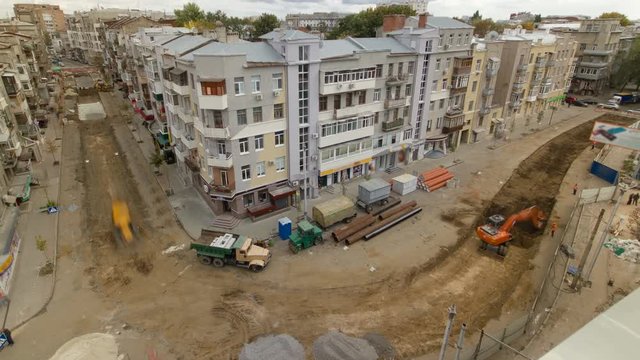 Industrial excavator loading soil material from road construction site into a dumper truck timelapse