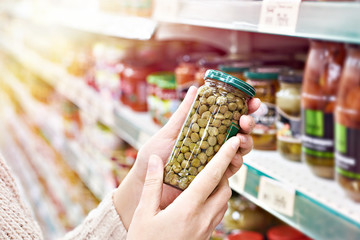 Hands with can of canned capers in store