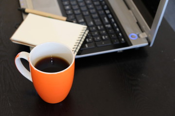 Laptop, coffee, notepad and pen on wooden coffee table