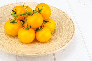 Bunch of ripe yellow tomatoes on white wooden table