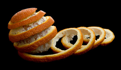 Peeled orange on black background. Removed peel formed a spiral tape. Looks like dancing orange with the ribbon. Side view.