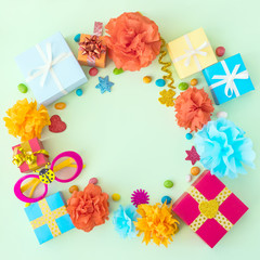 Birthday party background with festive decor, carnival glasses, ribbons, gift boxes, garland, pompoms on light background. Colorful celebration background, copy space, Flat lay, top view.