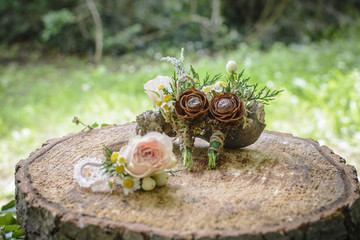 weeding boutonnieres with rose and pine cone on a wooden stump.