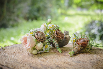 weeding boutonnieres with rose and pine cone on a wooden stump.