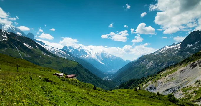 footage of the mont blanc massif near chamonix in the french alps showing clouds moving against blue summer sky and green alpine meadows