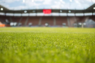 Foto op Plexiglas Voetbal Gras met voetbalstadion op de achtergrond.