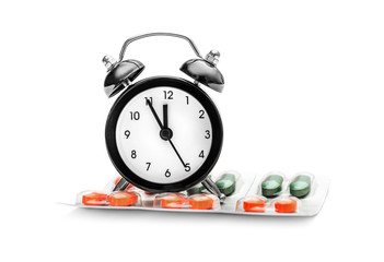 Clock with capsules in blister on white.