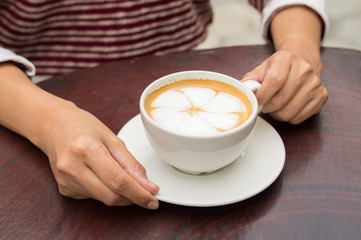 Woman holding coffee cup in hand.
