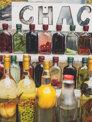 traditional georgian alcohol drink chacha in bottles with different fruits and herbs at market