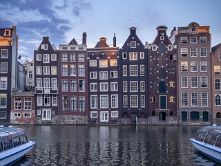 Naklejka premium Historic buildings on the Damrak canal in the centre of beautiful Amsterdam at night.