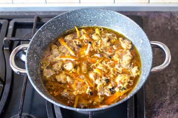 Meat with vegetables in frying pan wok on stove