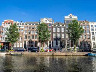 Amsterdam canal, bridge and typical houses, boats and bicycles during the day, Holland, Netherlands.