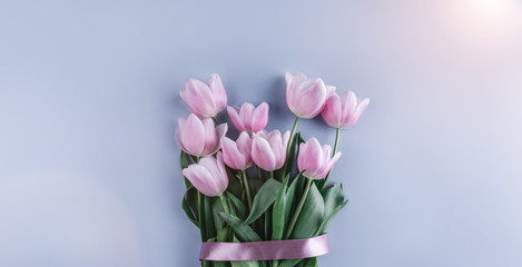 Bouquet of pink tulips flowers on blue background. Waiting for spring. Greeting card or wedding invitation. Flat lay, top view