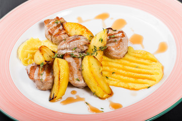 Roasted potatoes with chicken meat and herbs in plate on dark wooden background. Hot Meat Dishes. Top view, flat lay
