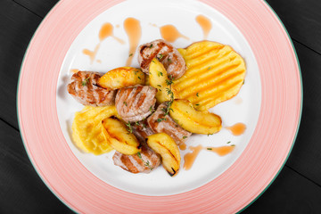 Roasted potatoes with chicken meat and herbs in plate on dark wooden background. Hot Meat Dishes. Top view, flat lay