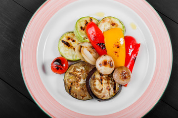 Grilled vagetables, mushrooms, tomatoes, eggplant on plate on wooden background. Healthy food