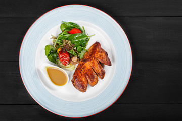 Grilled meat steak and salad with grilled vegetables, arugula and spinach in plate on dark wooden background. Hot Meat Dishes